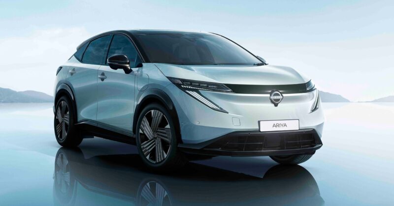 Lys grøn Nissan Ariya skråt forfra på blålig baggrund.