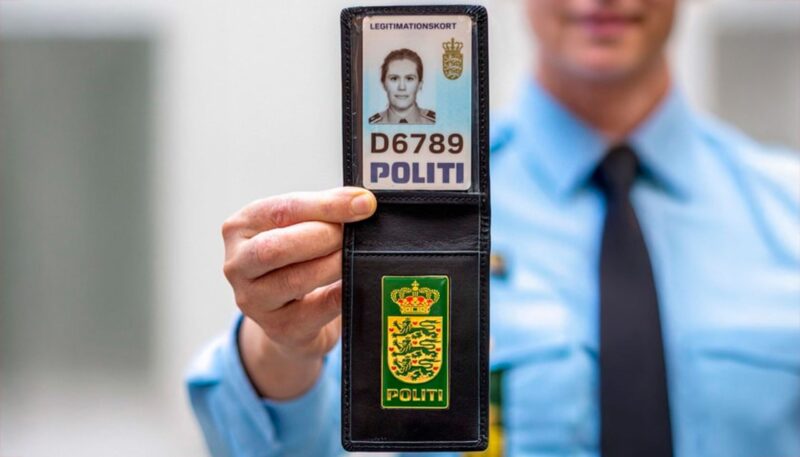 Politiskilt med uskarp politimand i baggrunden