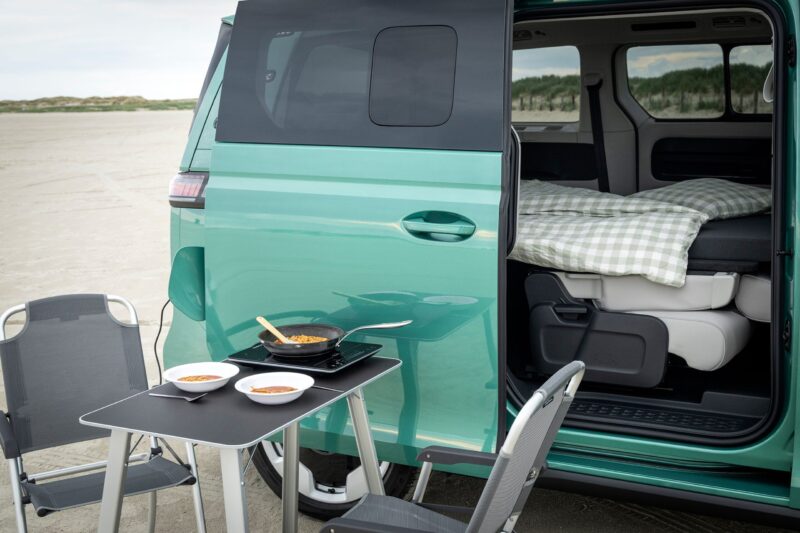 Grøn ID. Buzz med åben skydedør og campingmøbler.