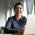 Storsmilende kvinde foran computer på arbejdspladsen