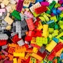 En stor bunke forskellige farverige plastikbyggeklodser, herunder røde, gule, grønne, blå, orange, pink, grå, sorte og hvide klodser, der er spredt i et tilfældigt arrangement.