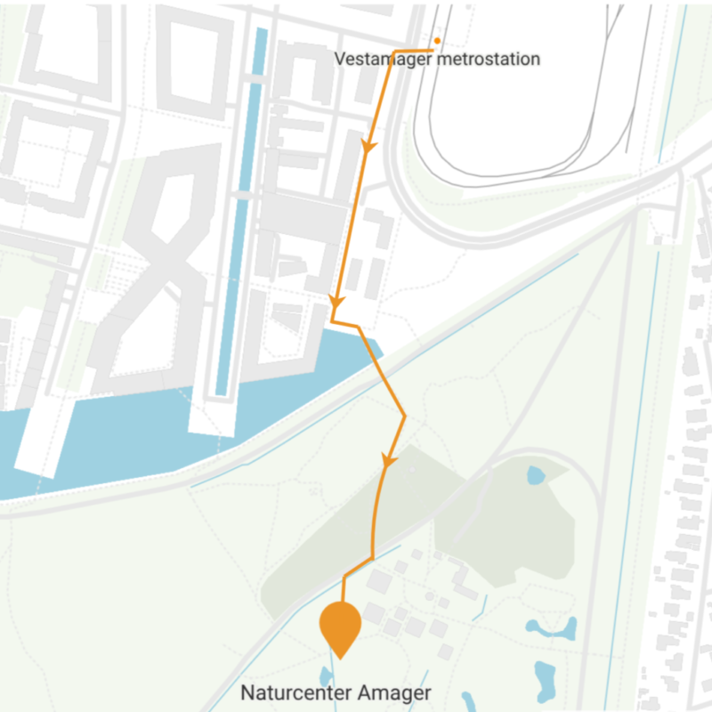 En orange linje viser en gåtur fra metrostationen Vestamager, der går mod syd gennem grønne områder og slutter ved Naturcenter Amager. Pilene angiver retningen på stien.