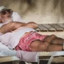 Foto af en ældre mand, der ligger og sover på en solstol